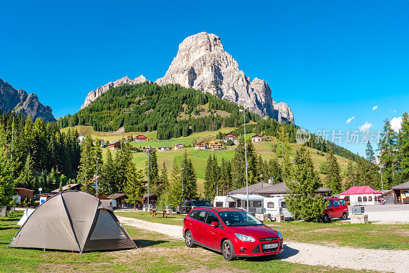 神奇的花岗岩白云石峰，Sassongher，高山松树和云杉森林和营地的山谷与帐篷和汽车在Colfosco, Corvara在蓝天，阳光灿烂的日子，南蒂罗尔，阿尔卑斯山，意大利。